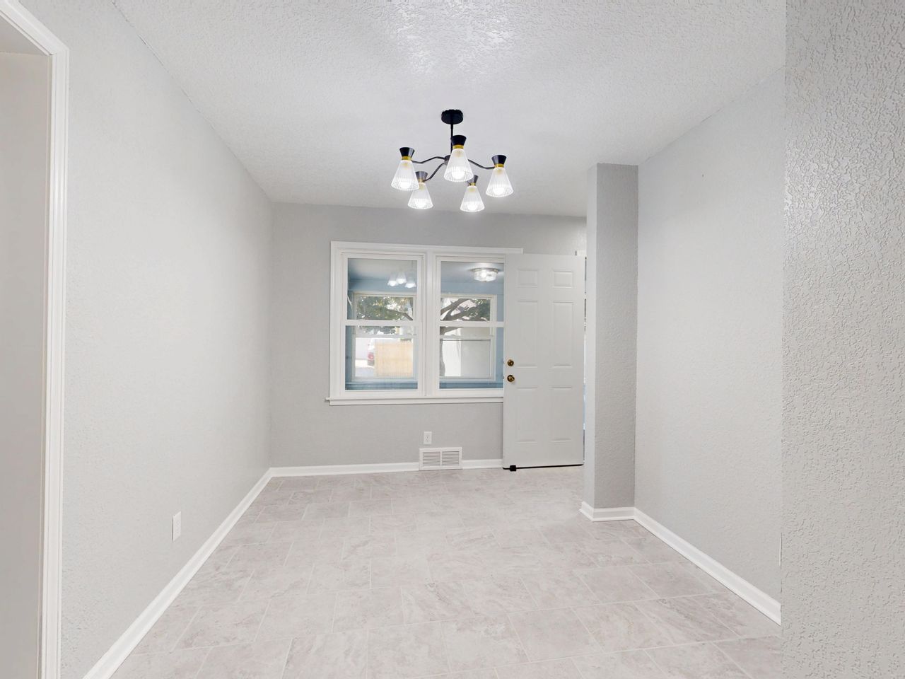 A spacious, empty room with a modern light fixture and large windows showcasing a minimalist design.
